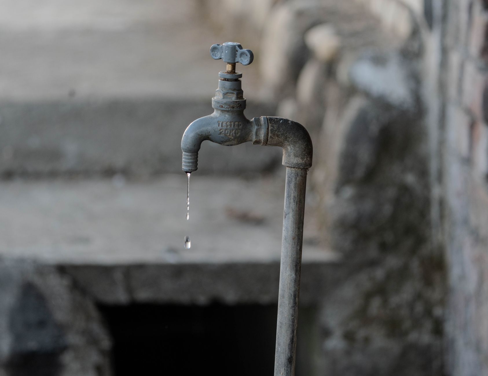 En gammel udendørs vandhane, der drypper